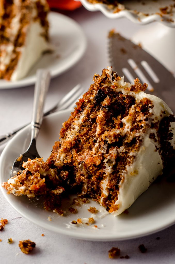 slice of carrot walnut cake on a white plate with a fork
