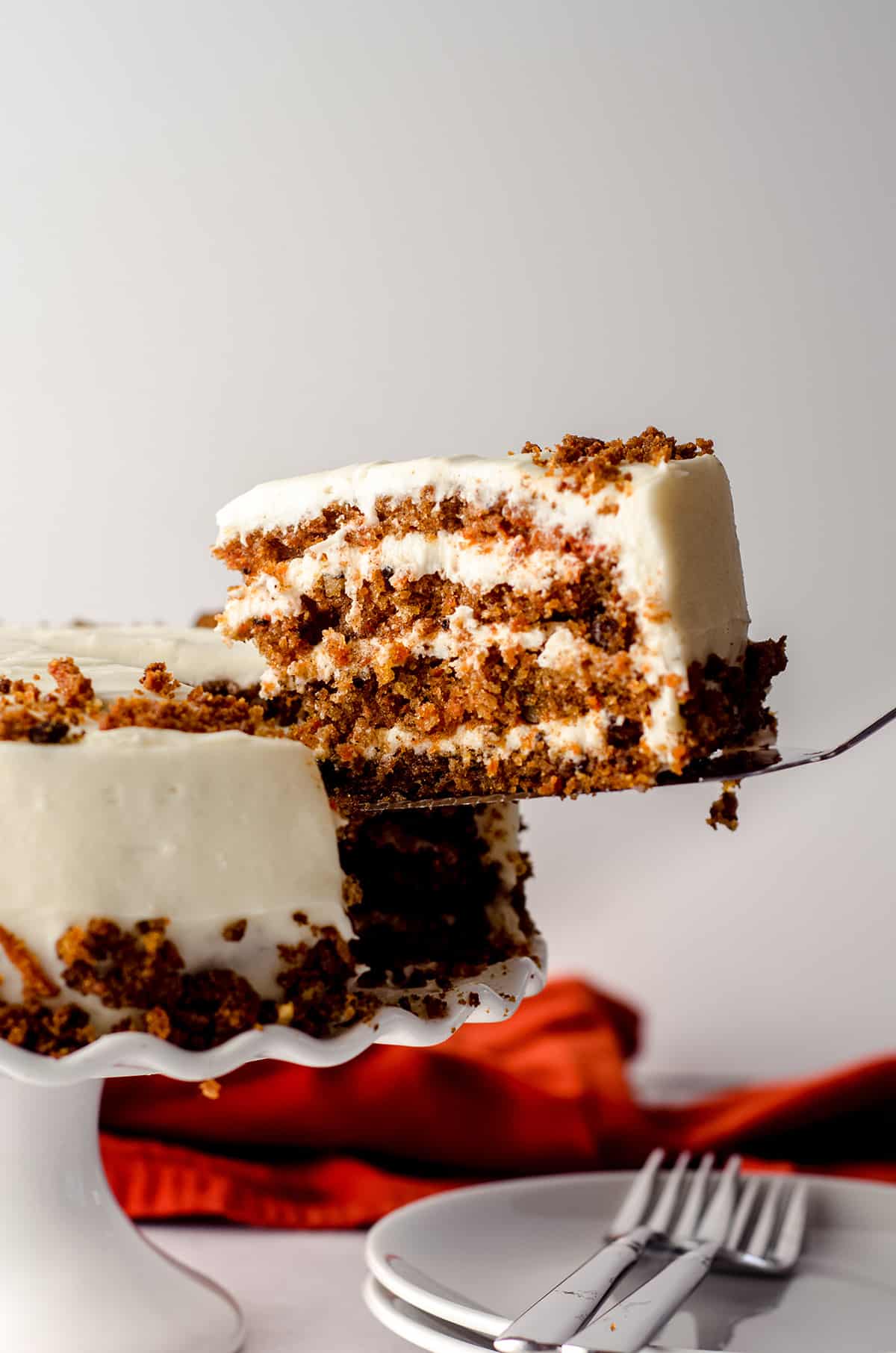 a slice of carrot walnut cake being lifted out from the cake to serve