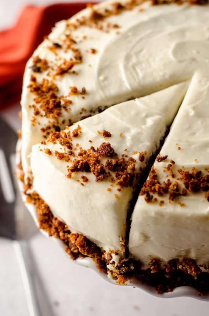 carrot walnut cake on a cake stand and cuts made for a slice to serve