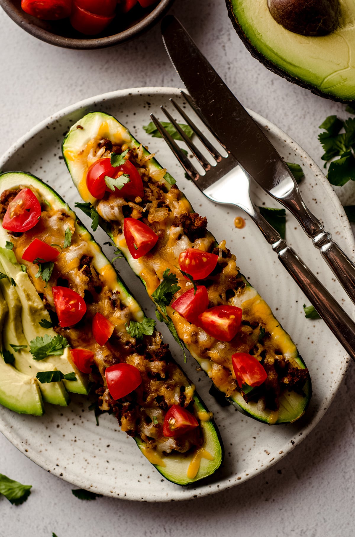 aerial photo of taco zucchini boats on a plate with a fork and a knife