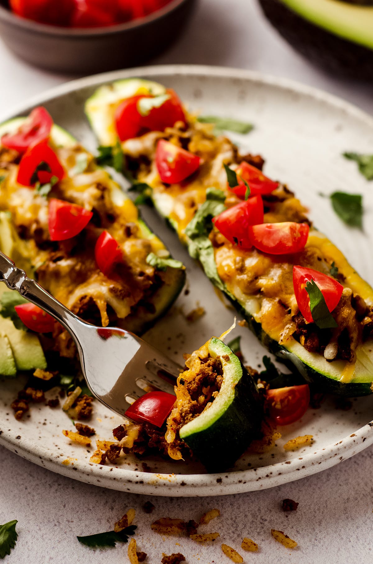 taco zucchini boats on a plate with a fork holding a bite