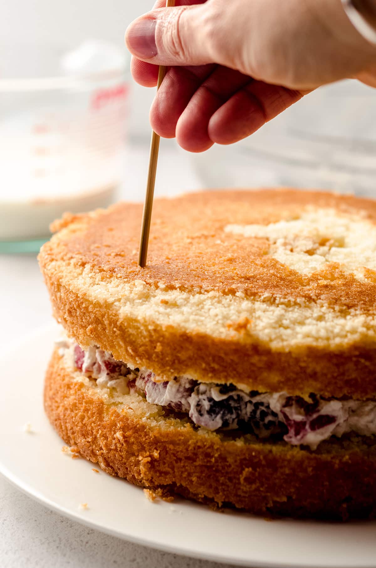 poking holes into a milk and berries cake