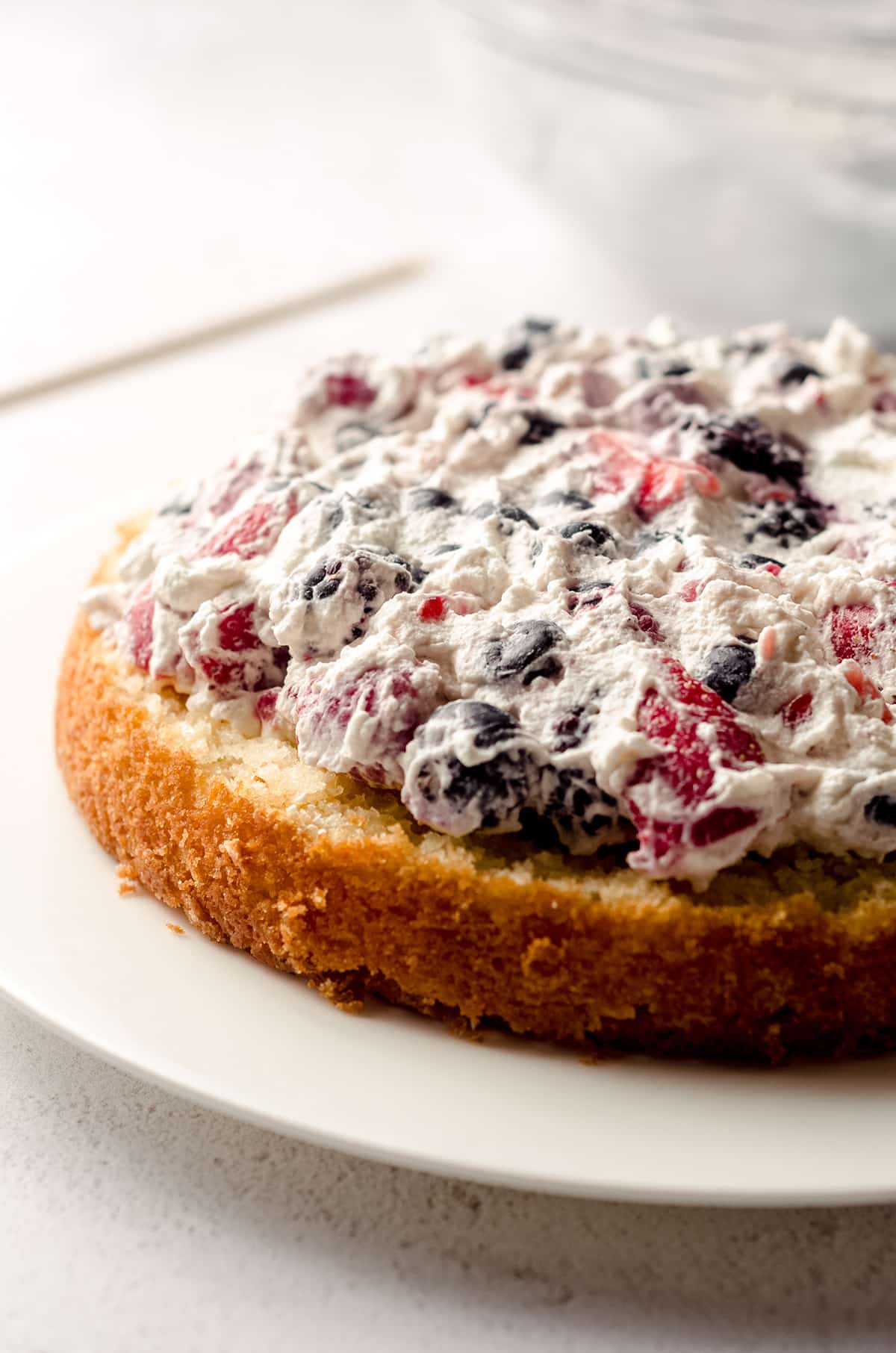 whipped cream and berry filling on a layer of berry cake