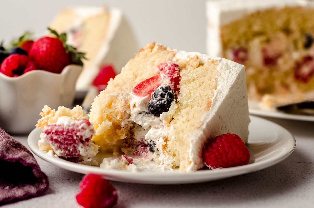 slice of berry cake with a bite taken out of it on a plate with a fork