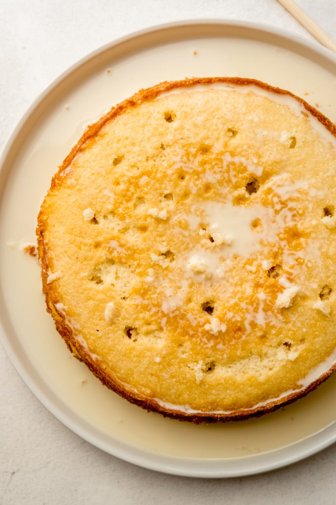 Aerial photo of a layer of cake with holes poked in it and a soaking syrup poured onto it.