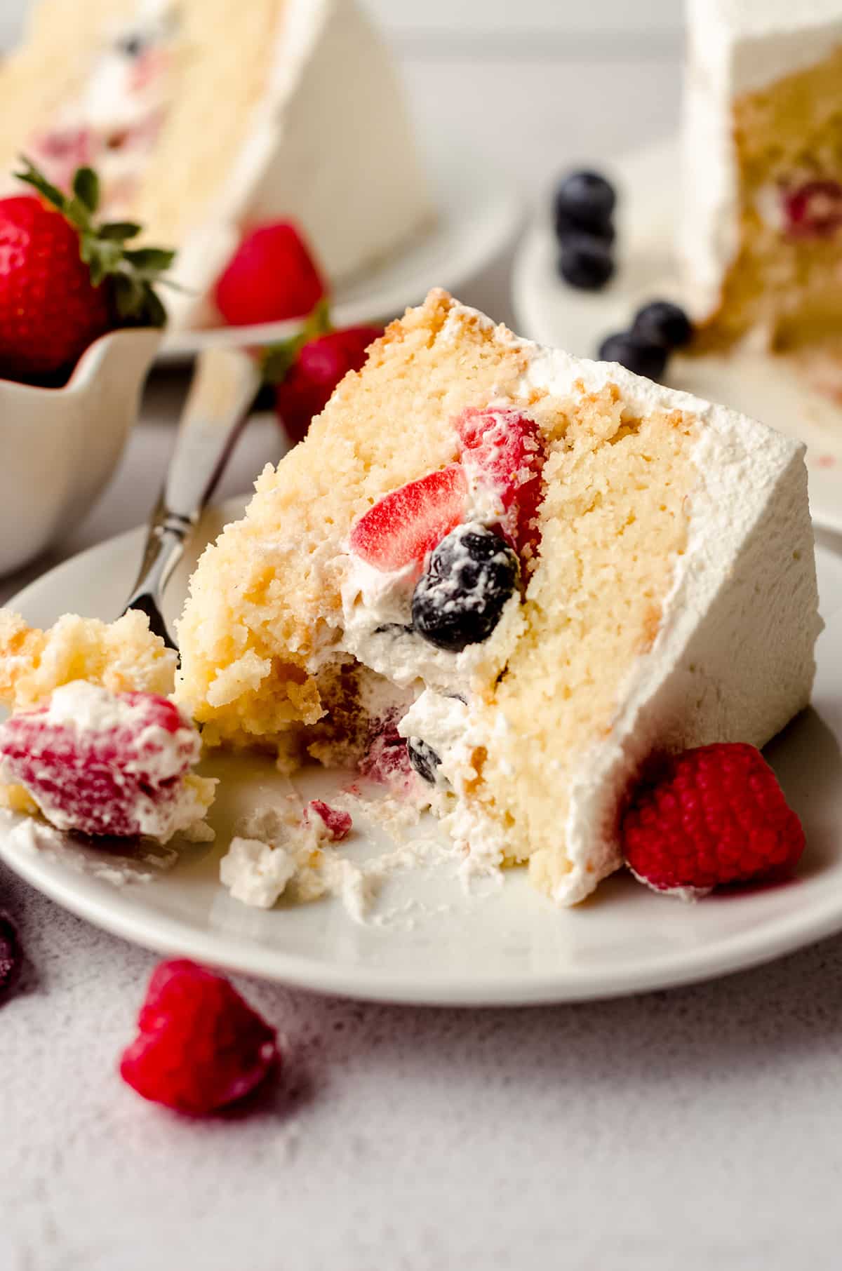 slice of berry cake with a bite taken out of it on a plate with a fork