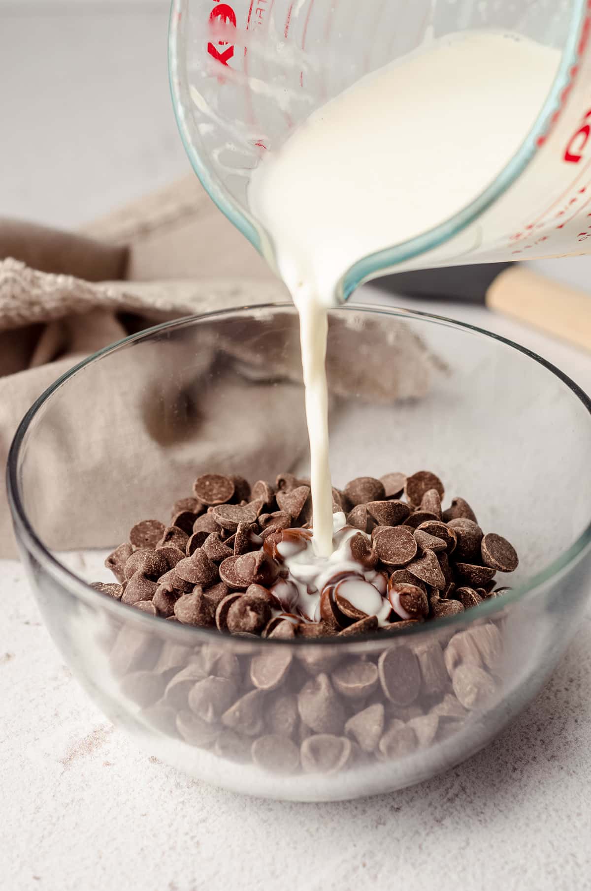 pouring heated cream onto chocolate chips to make chocolate ganache