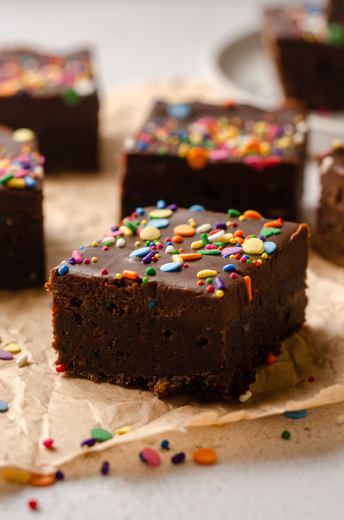 funfetti brownie on parchment with sprinkles scattered around it