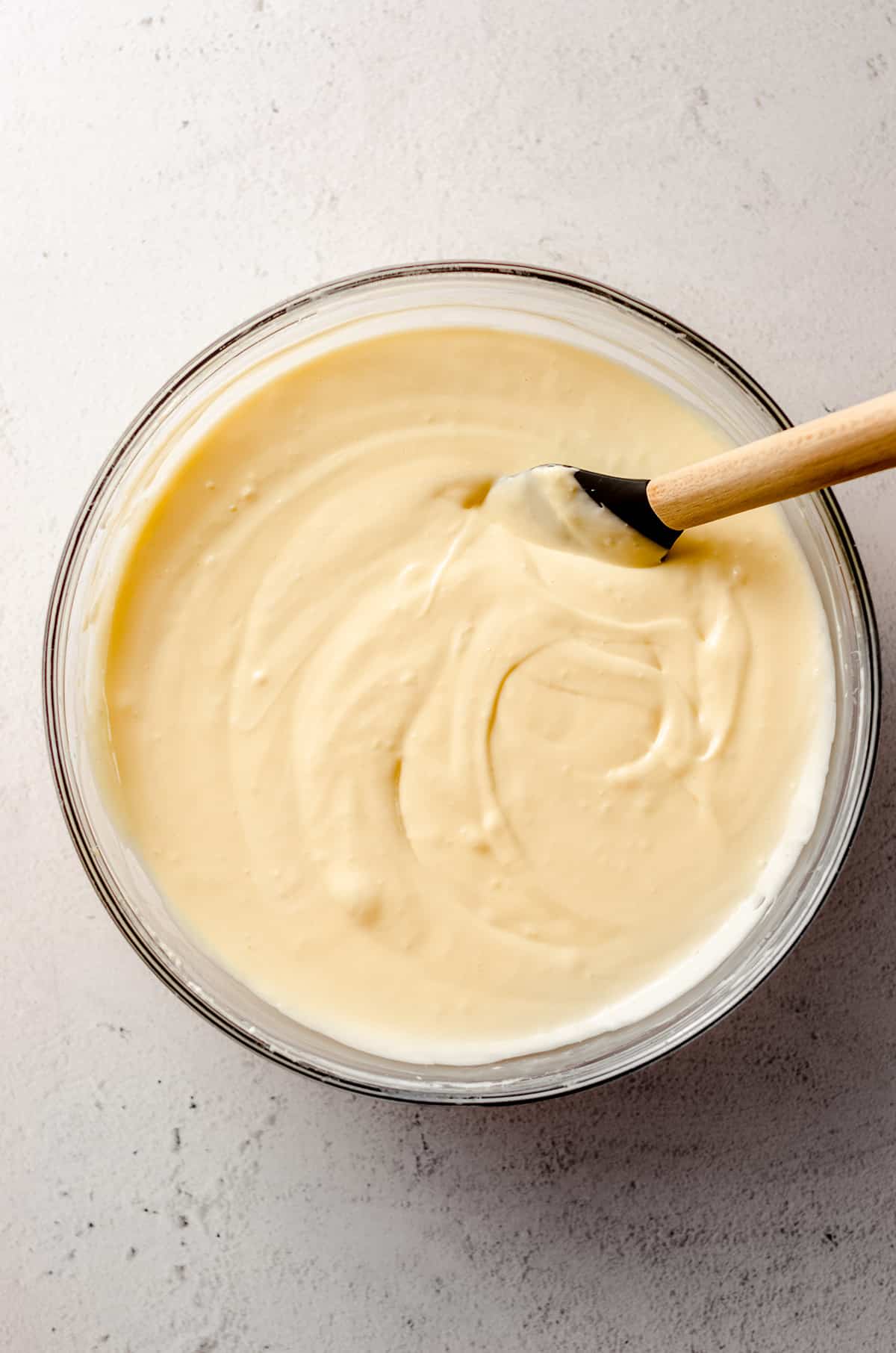 cheesecake batter in a glass bowl with a spatula