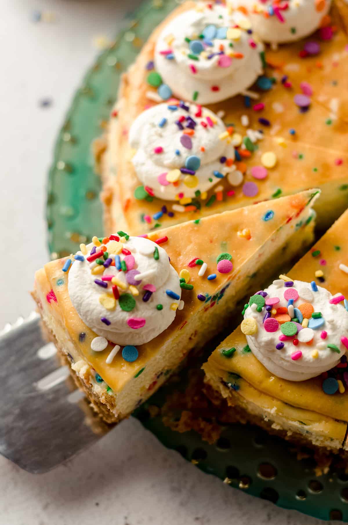 slice of funfetti cheesecake being removed with a spatula