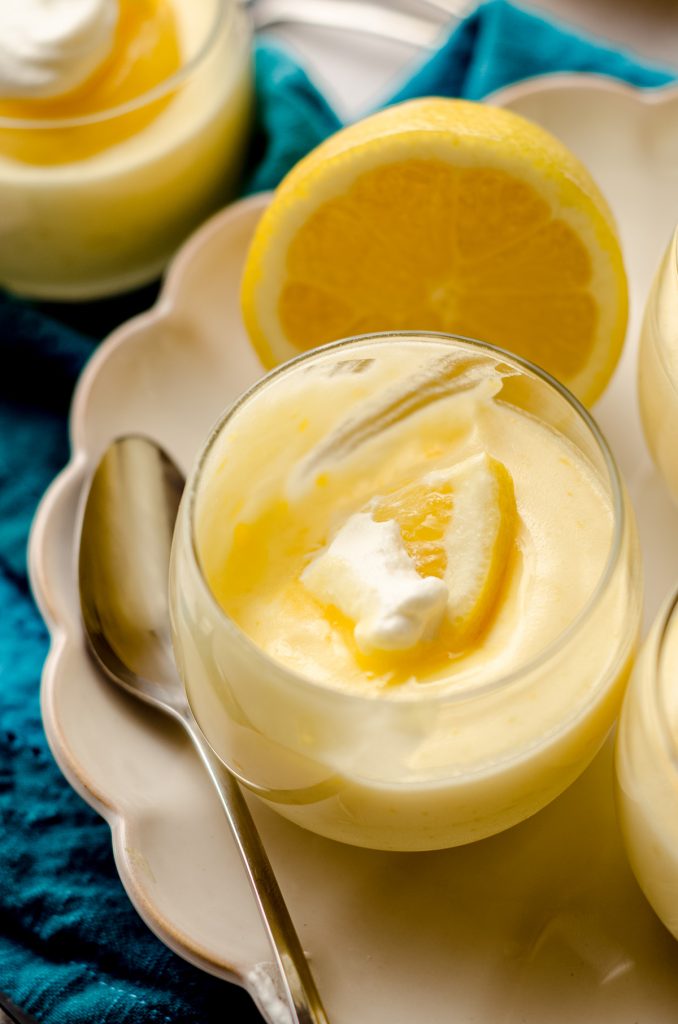 lemon mousse in a cup on a plate with a scoop taken out of it
