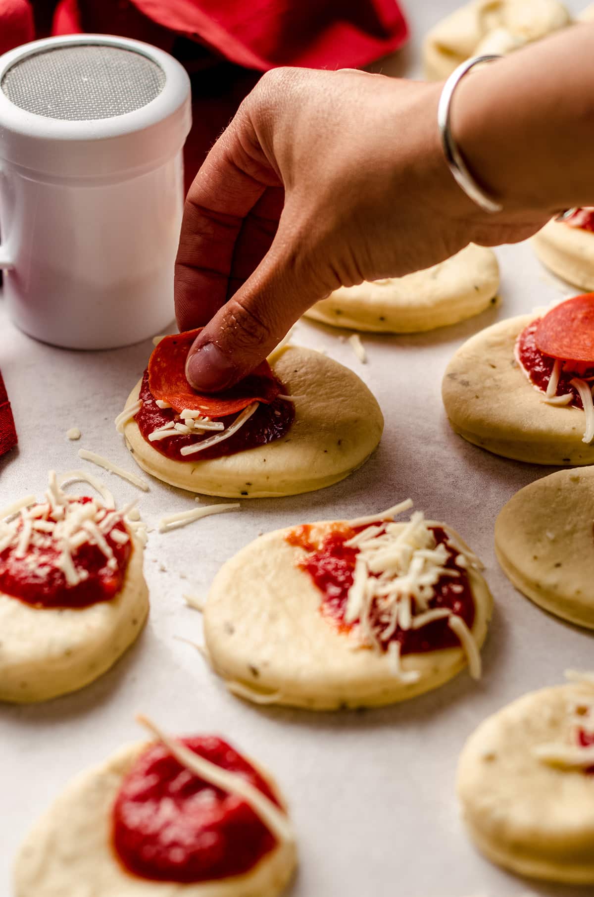 putting sauce, cheese, and pepperoni on rounds of dough for pizza pull apart bread