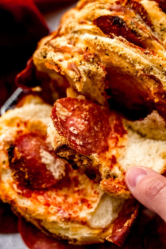Someone is pulling apart pizza pull-apart bread.
