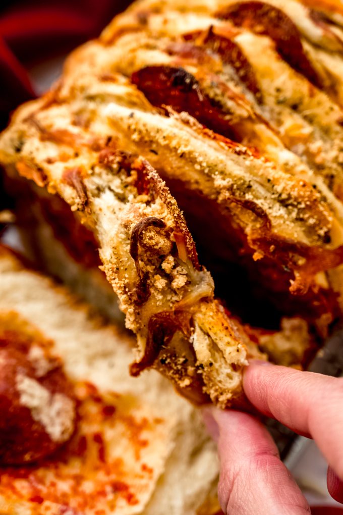 Someone is pulling apart pizza pull-apart bread.