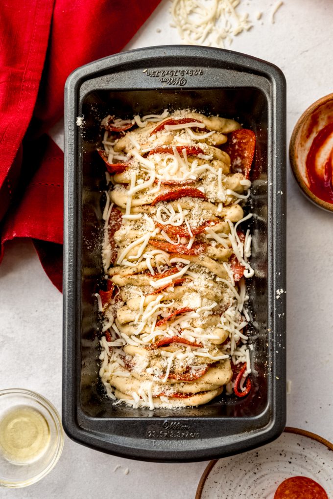 Aerial photo of pizza pull-apart bread in a loaf pan before baking.