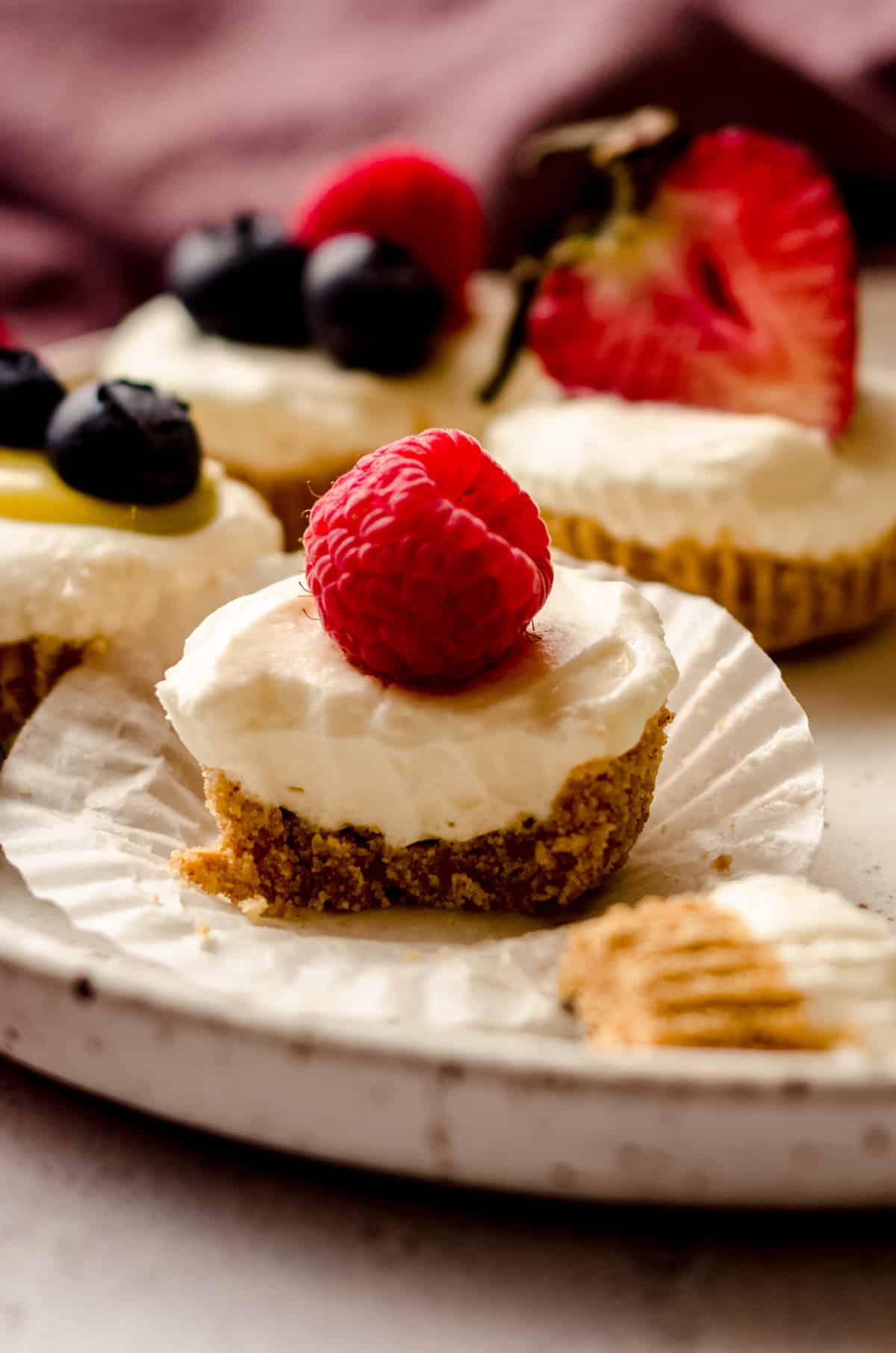 an unwrapped no bake cheesecake bite with a raspberry on top