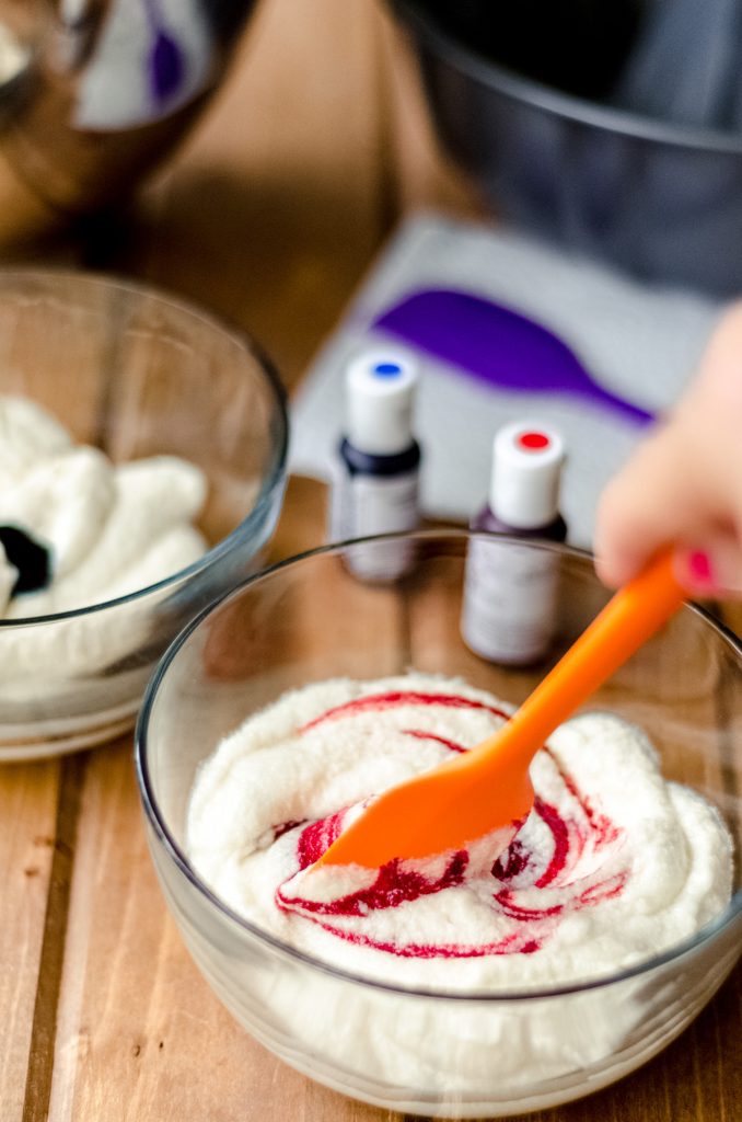 swirling red gel coloring into white cake batter