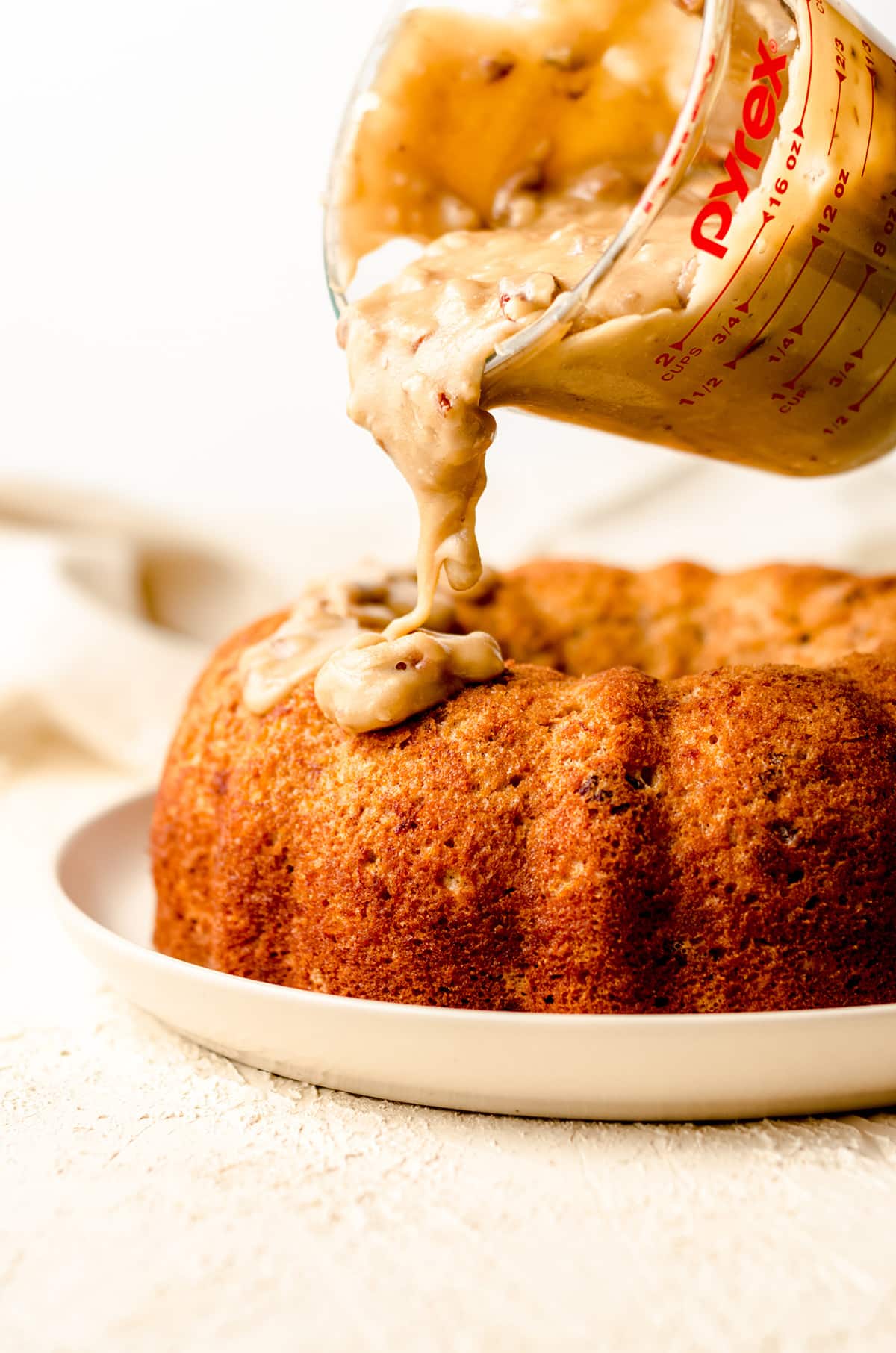 pouring pecan praline icing on a bananas foster cake