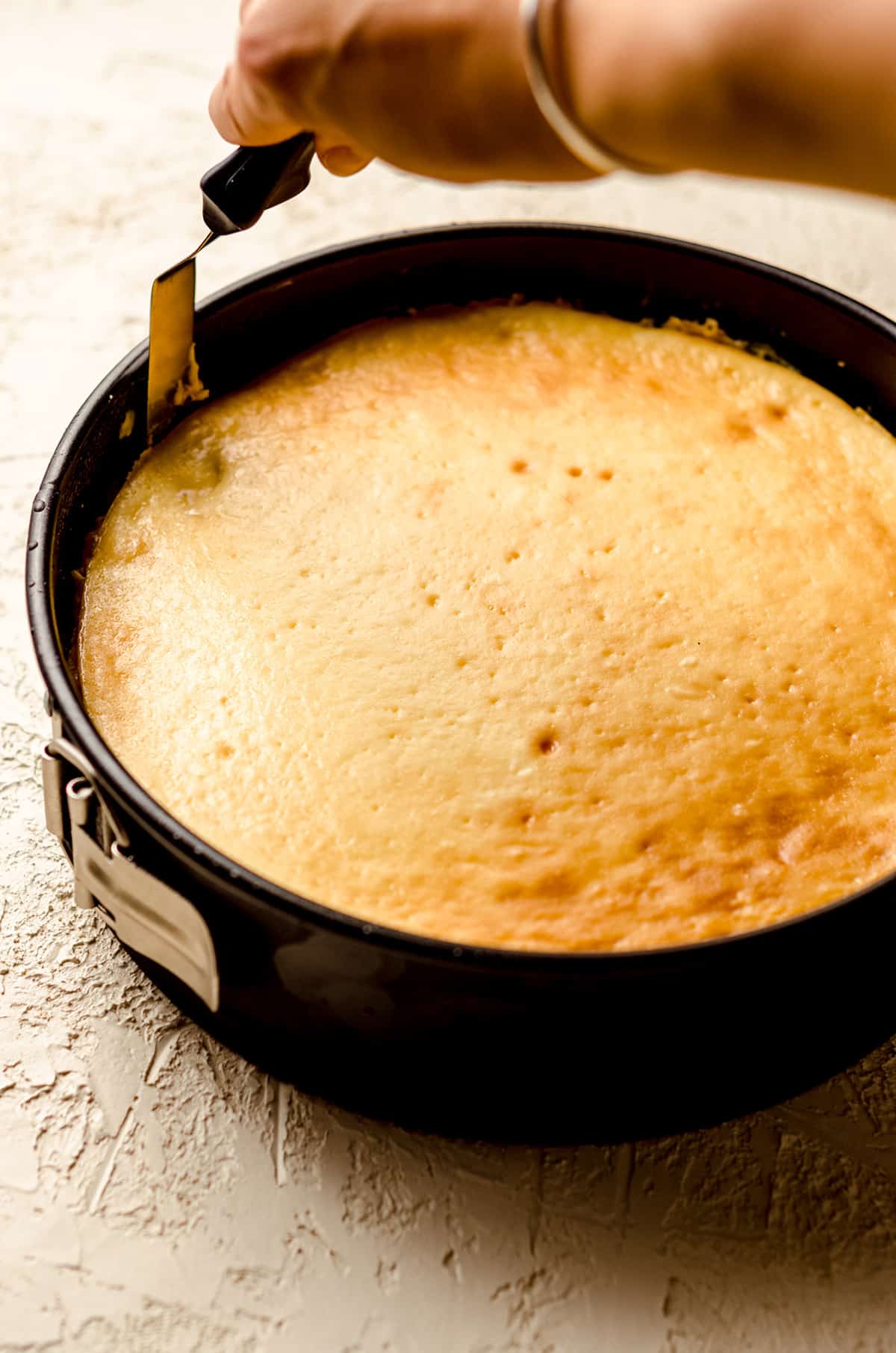 loosening peach cheesecake from the springform pan with a spatula