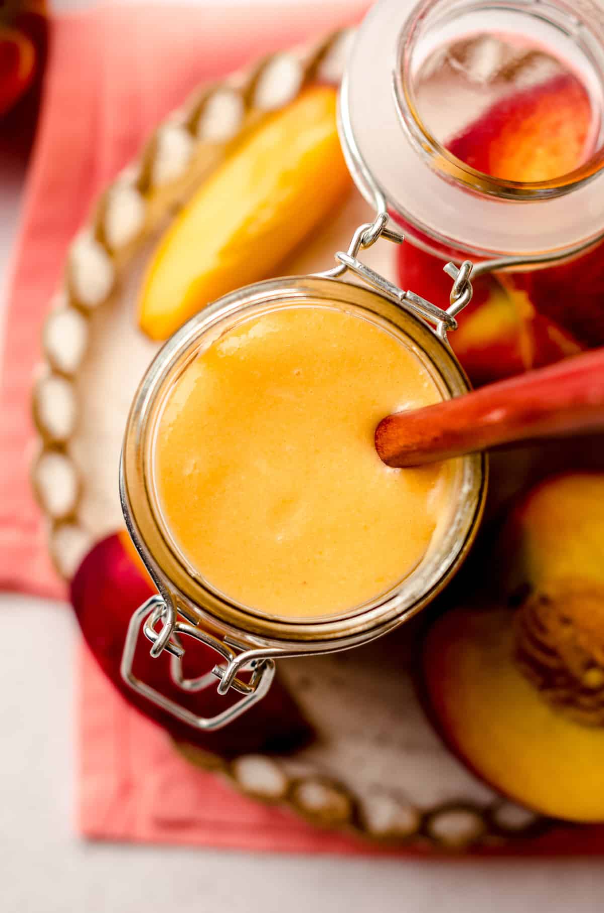 aerial photo of a jar of peach curd with a spoon in it