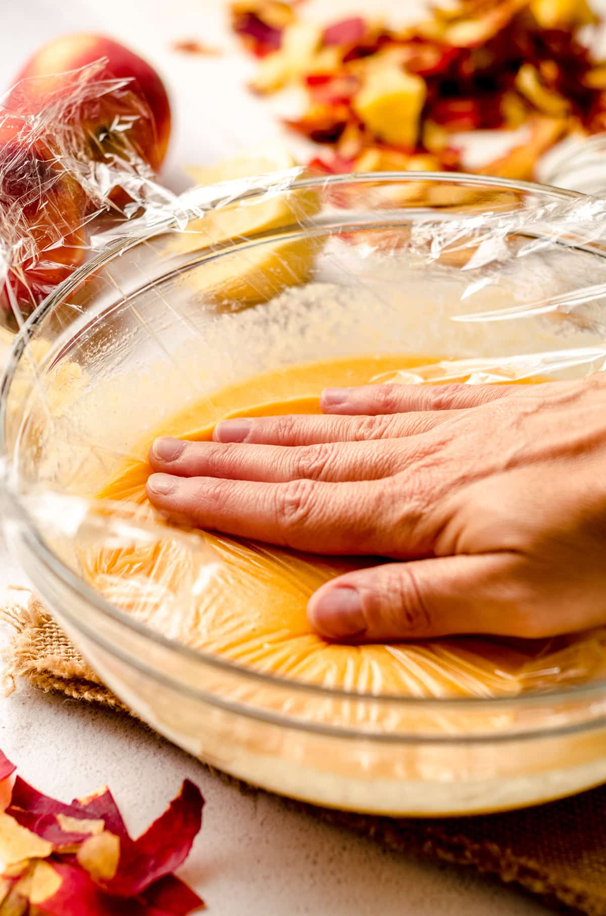 hand pressing plastic wrap onto peach curd