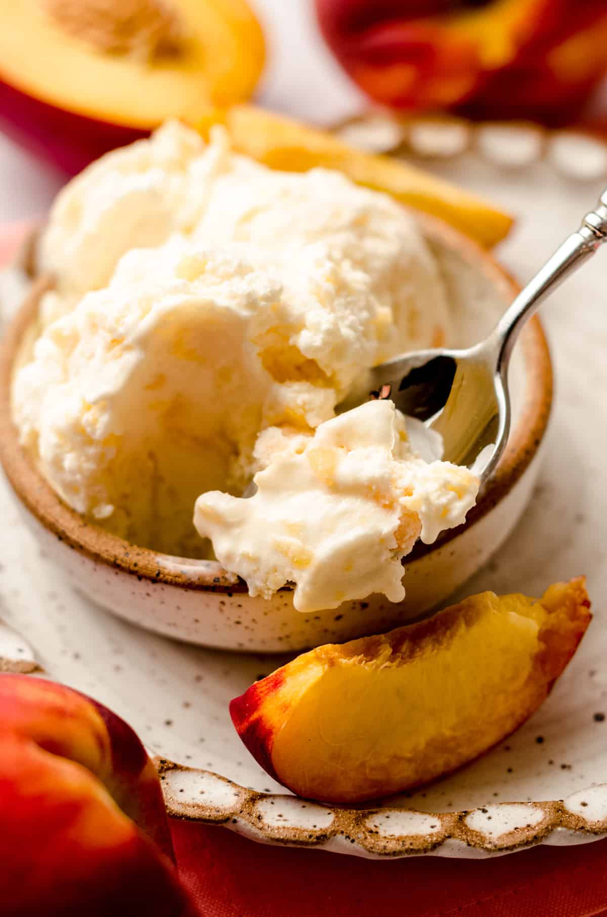 a bowl of homemade peach ice cream with a scoop a spoon