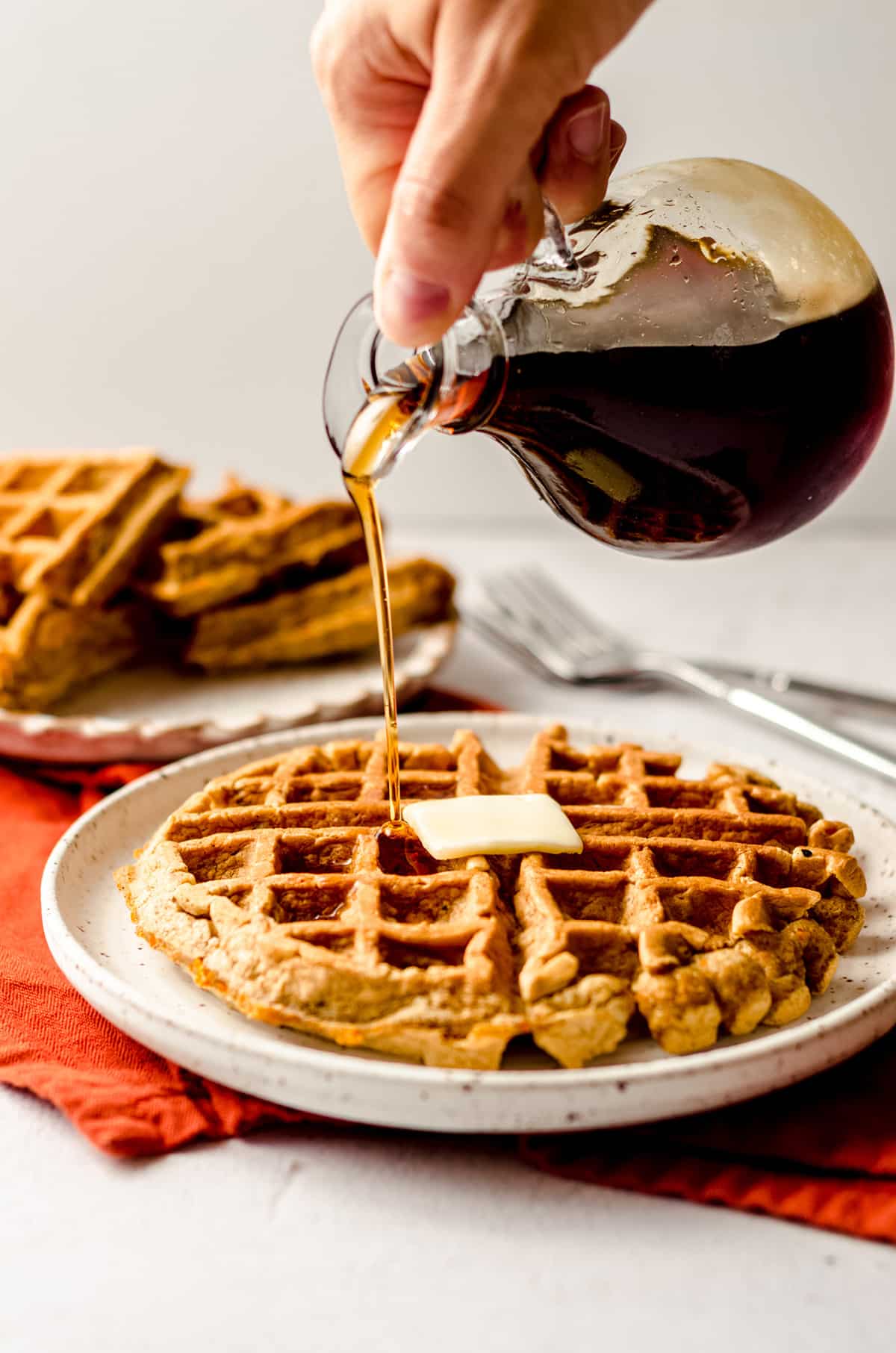 pouring syrup onto carrot cake waffles