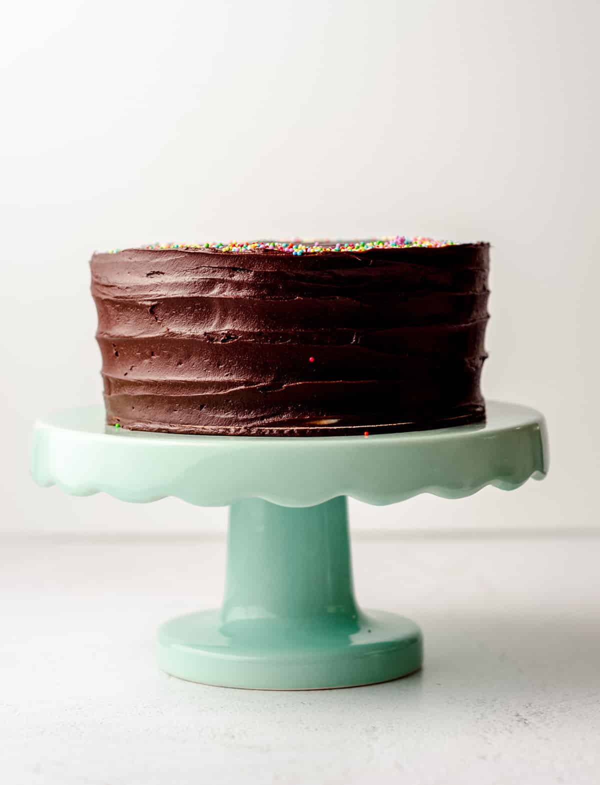 a small chocolate cake on an aqua cake stand