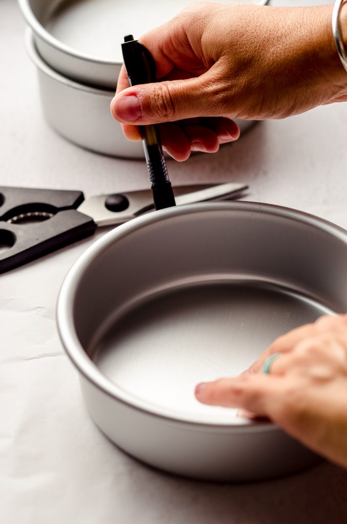 tracing a cake pan onto parchment paper to make parchment rounds