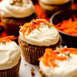 carrot cake cupcakes with cream cheese frosting with shredded carrots and pecans on top