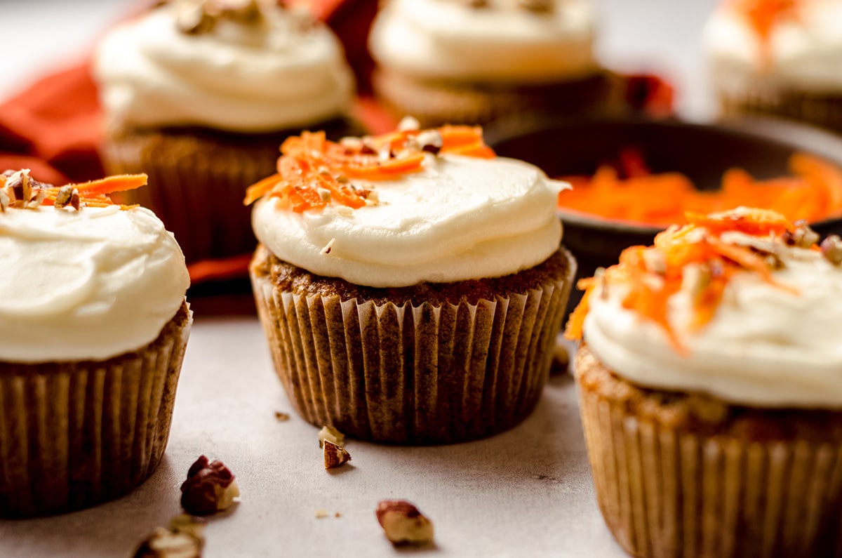 carrot cake cupcakes with cream cheese frosting with shredded carrots and pecans on top
