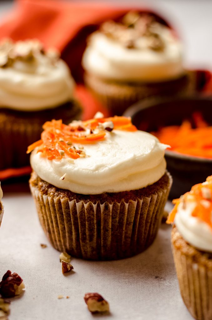 carrot cake cupcakes with cream cheese frosting with shredded carrots and pecans on top