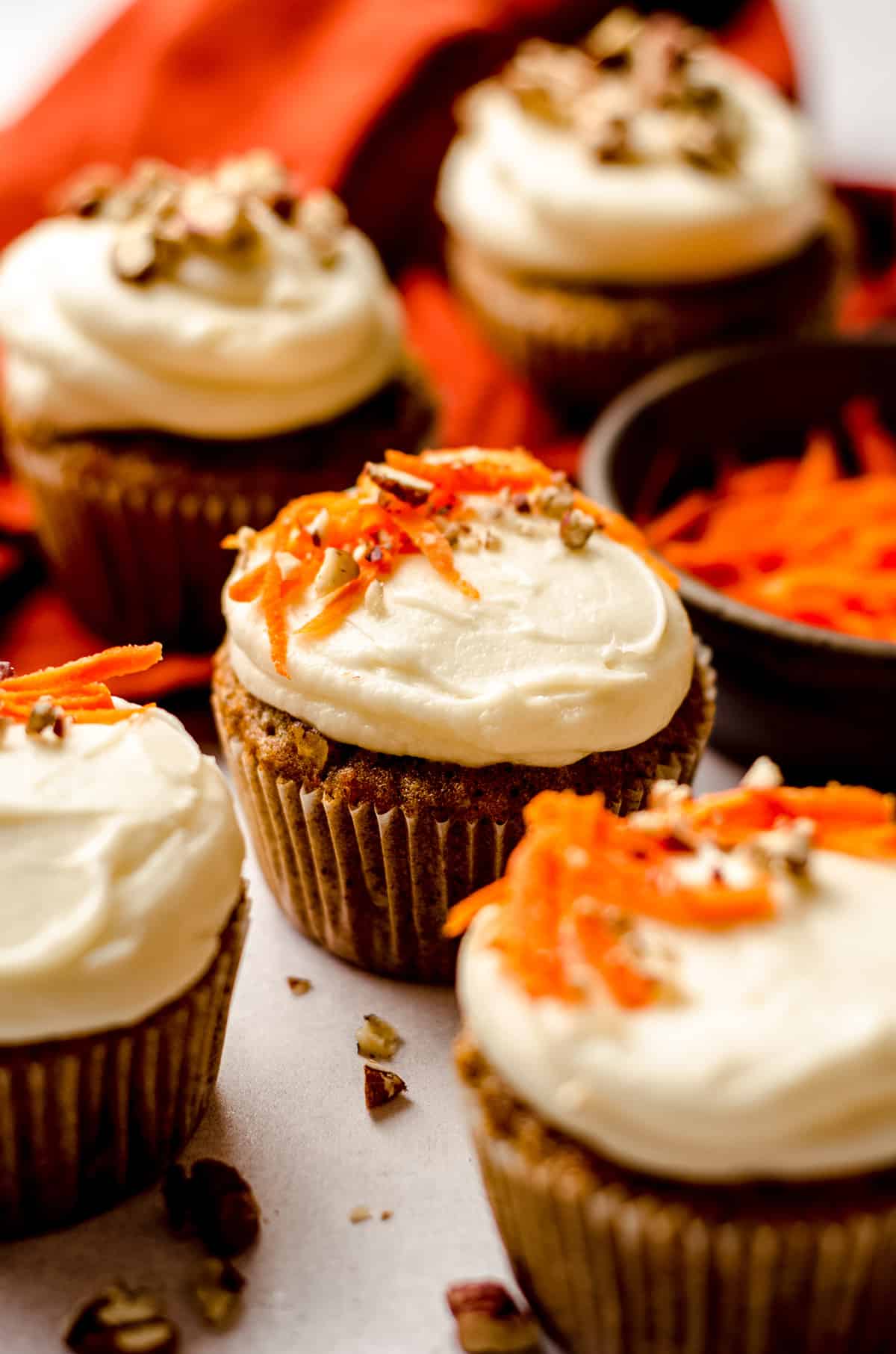 carrot cake cupcakes with cream cheese frosting with shredded carrots and pecans on top