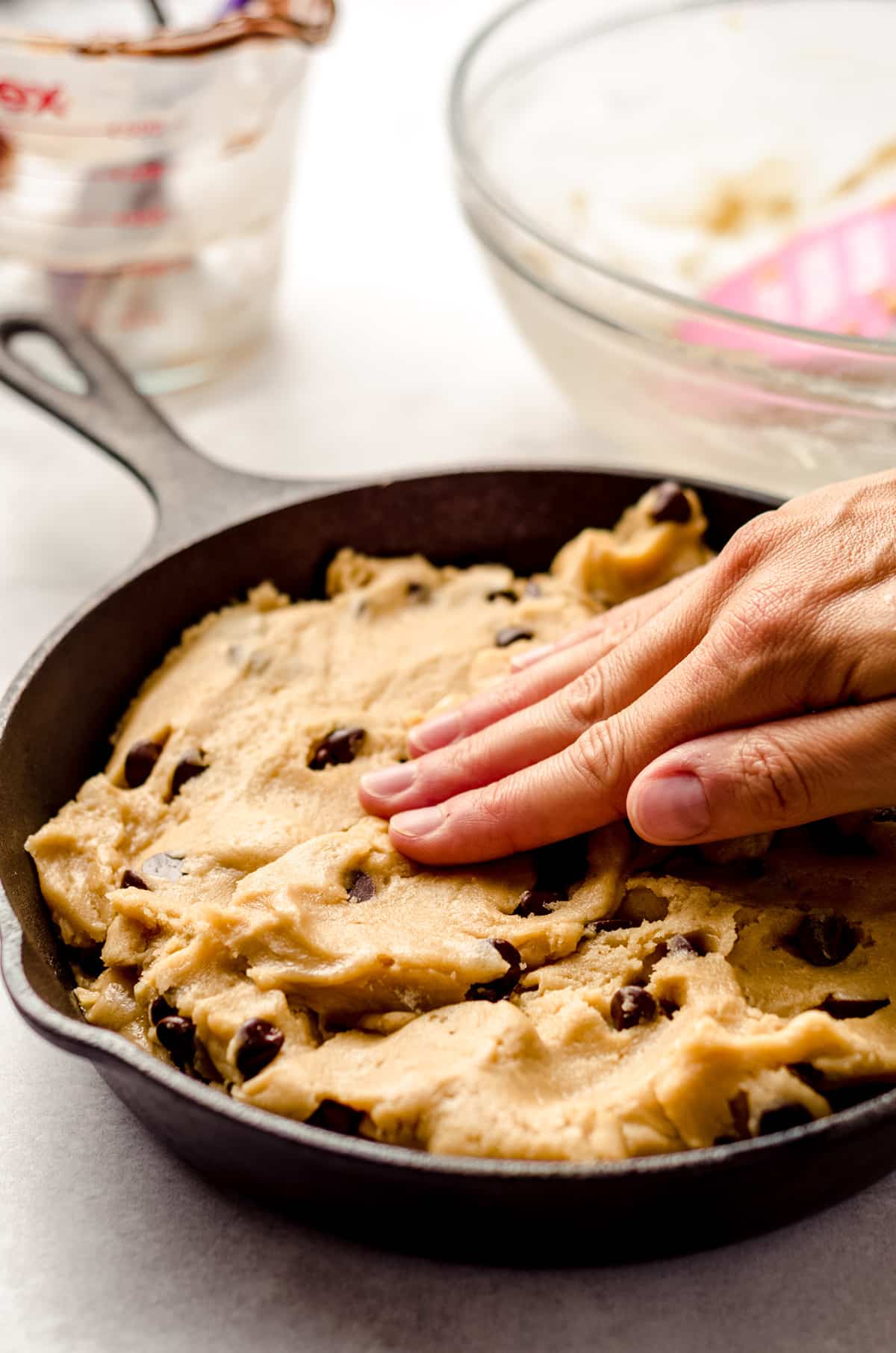 pressing cookie dough together in a skillet cookie