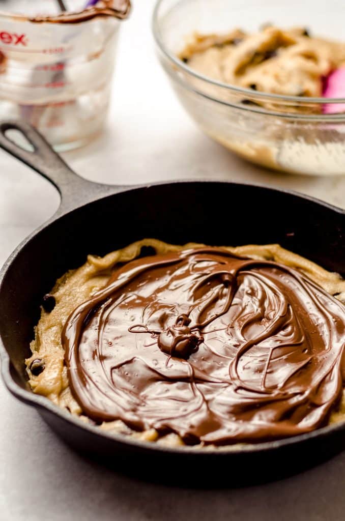 nutella on top of chocolate chip cookie dough in a skillet