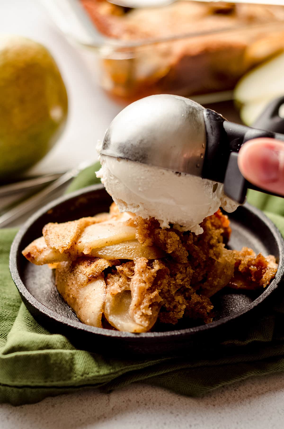 putting a scoop of ice cream on top of pear cobbler