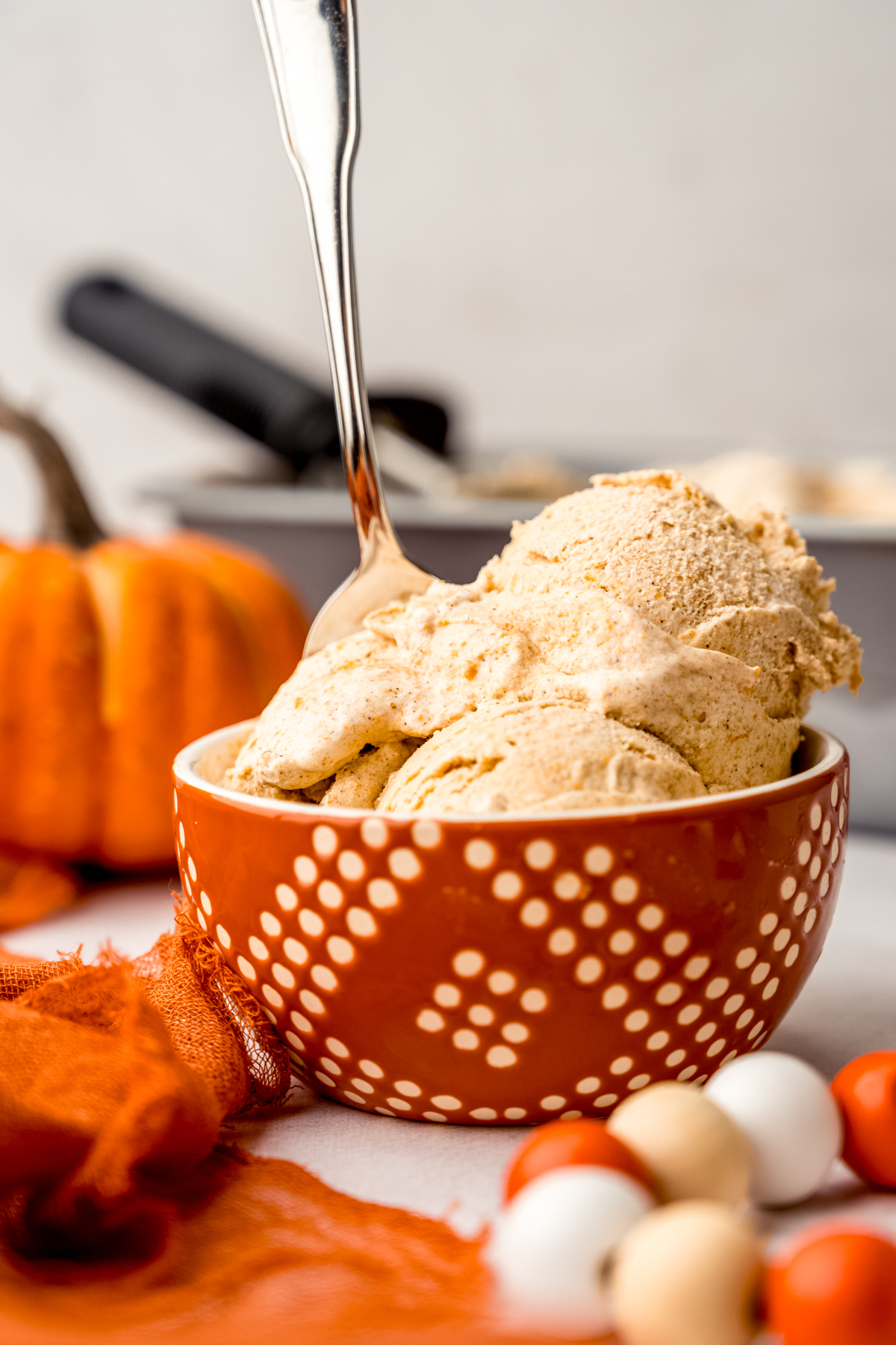 A bowl of pumpkin ice cream with a spoon in it.