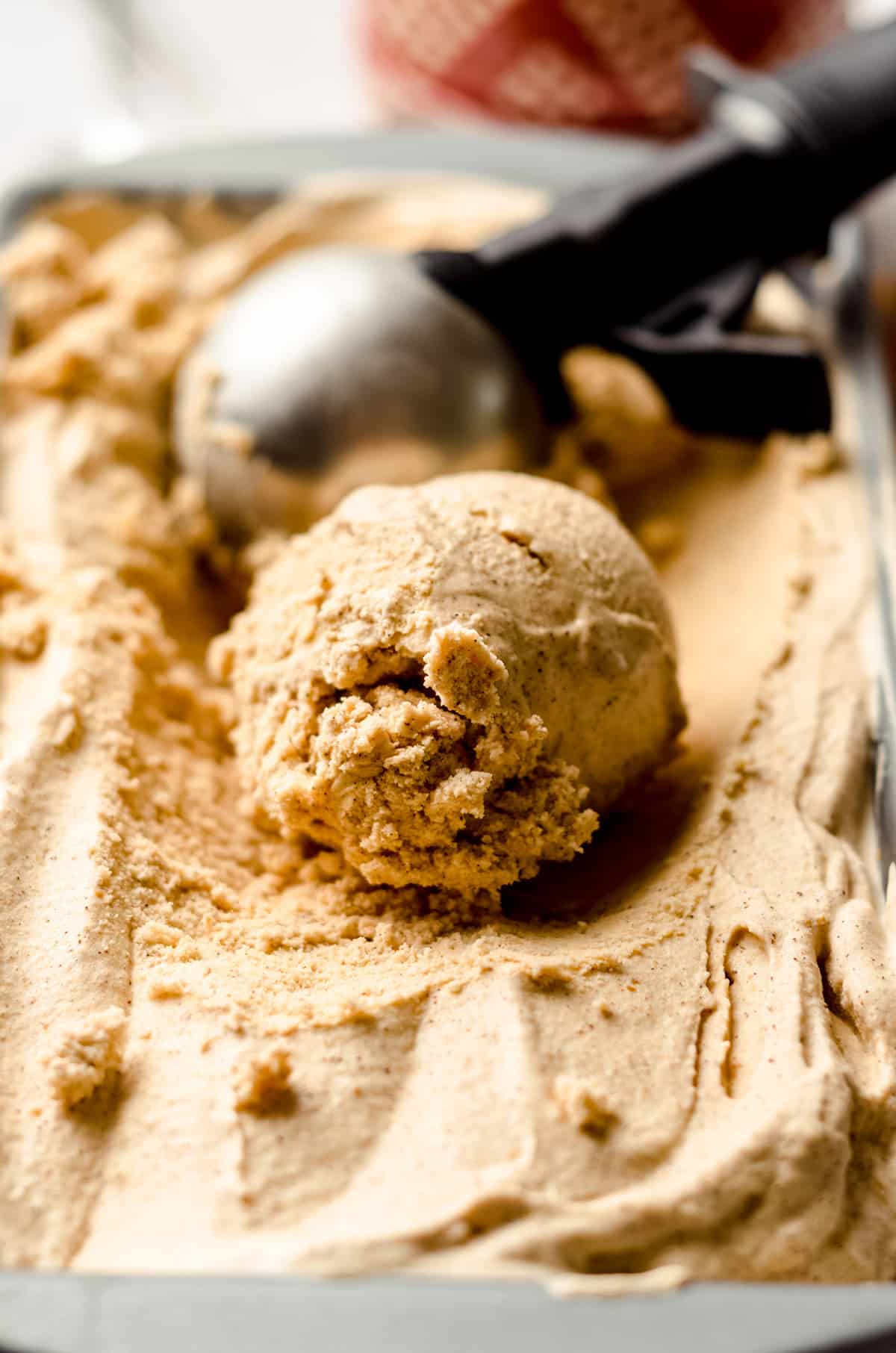 a scoop of pumpkin ice cream with an ice cream scooper in the background