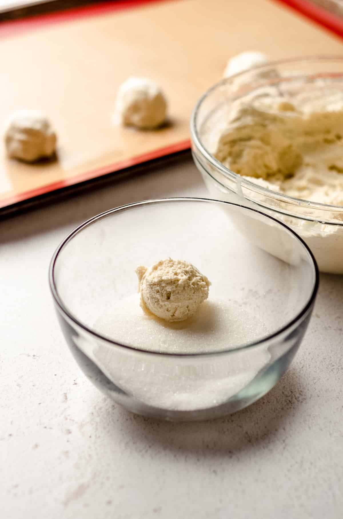 ball of vanilla bean sugar cookie dough in a bowl of sugar