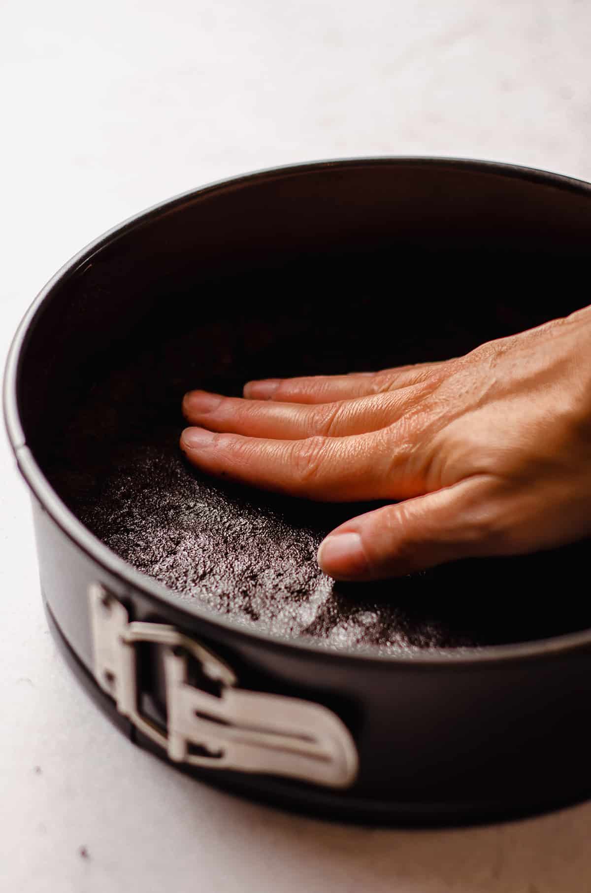 pressing oreo crust into a springform pan