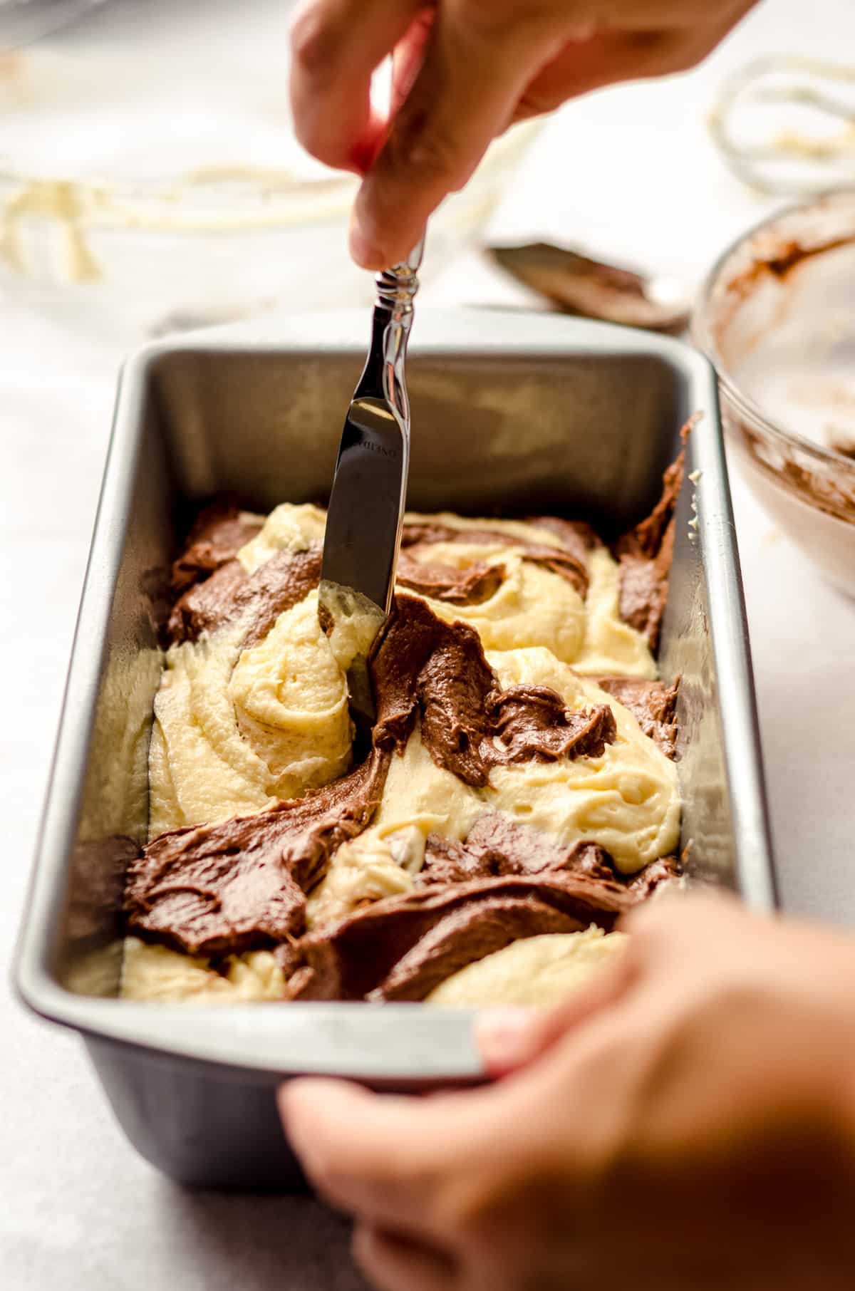 using a butter knife to swirl batter together for marble pound cake