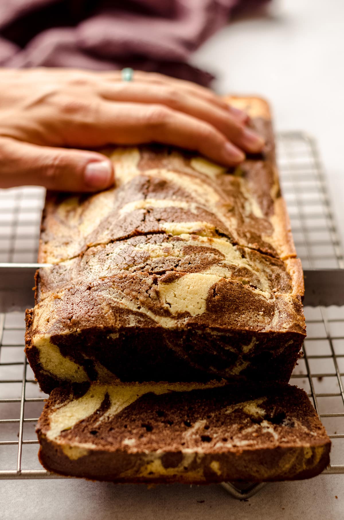 hand slicing a loaf of marble pound cake