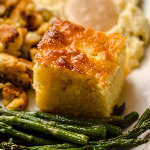 slice of skillet cornbread on a plate with other thanksgiving sides