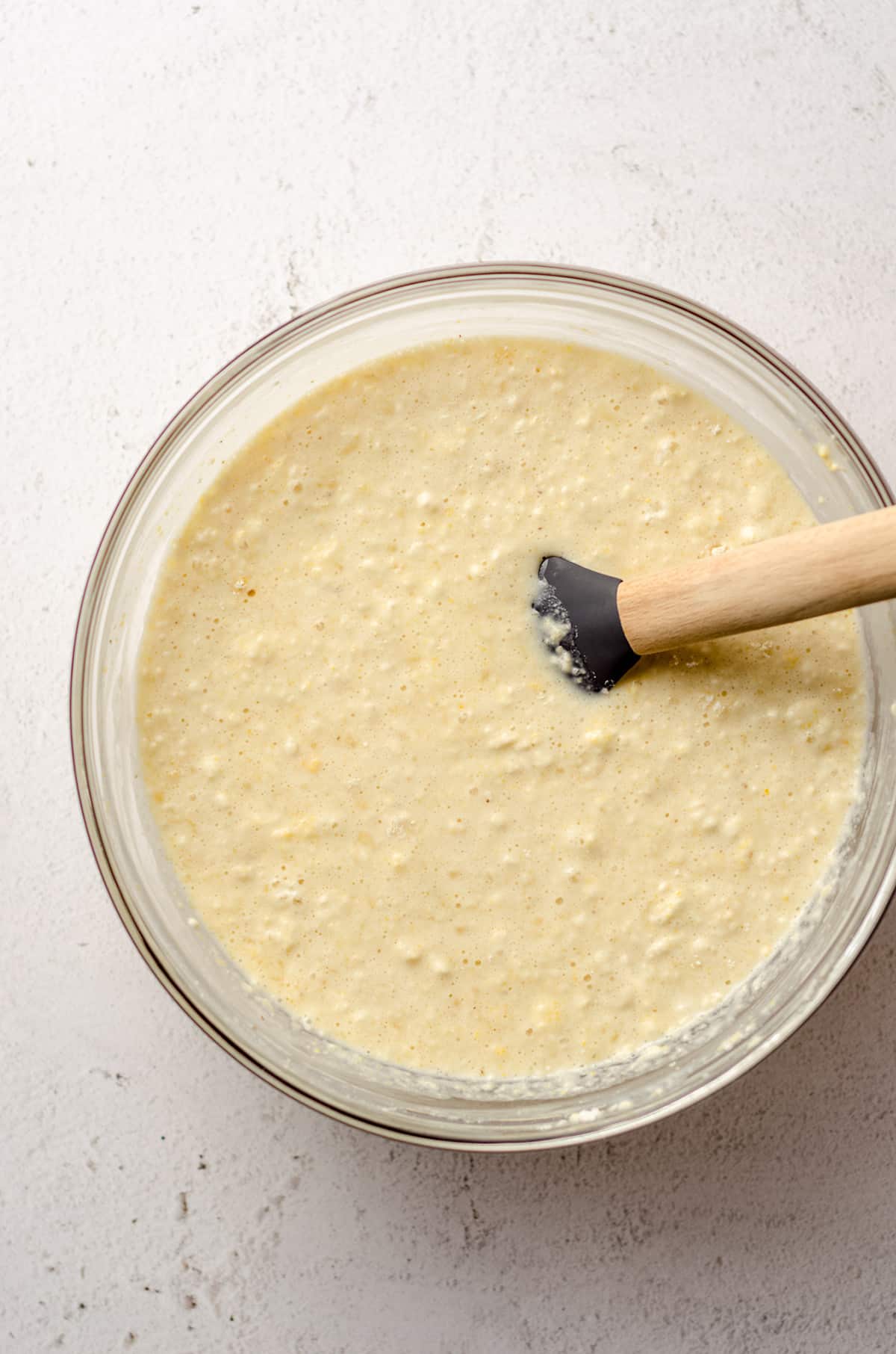 skillet cornbread batter in a glass bowl with a spatula