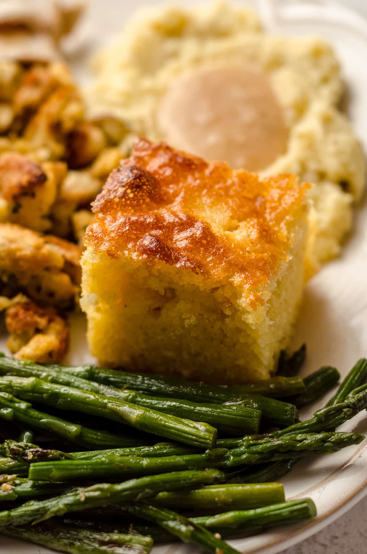 slice of skillet cornbread on a plate with other thanksgiving sides