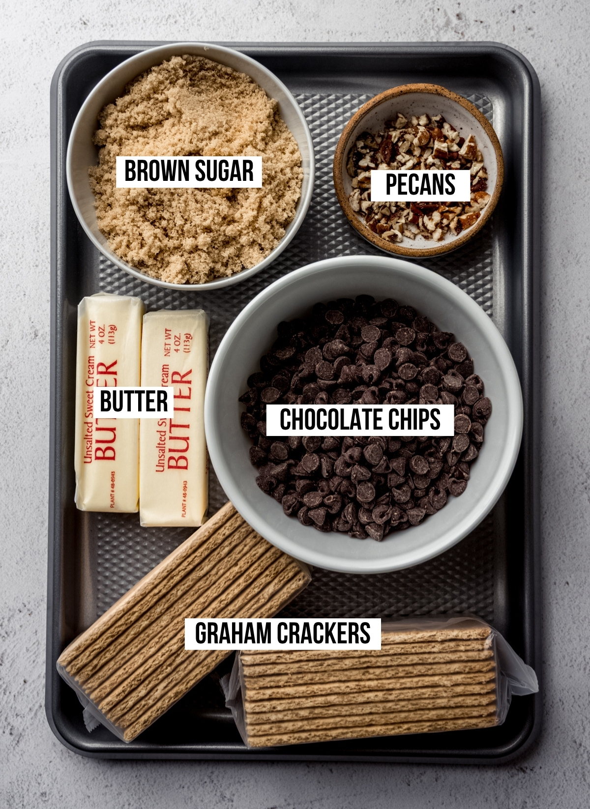 Aerial photo of ingredients to make graham cracker toffee bark with text overlay labeling each ingredient.