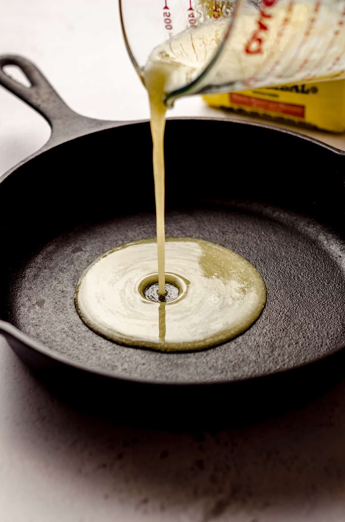 pouring melted butter into a cast iron skillet