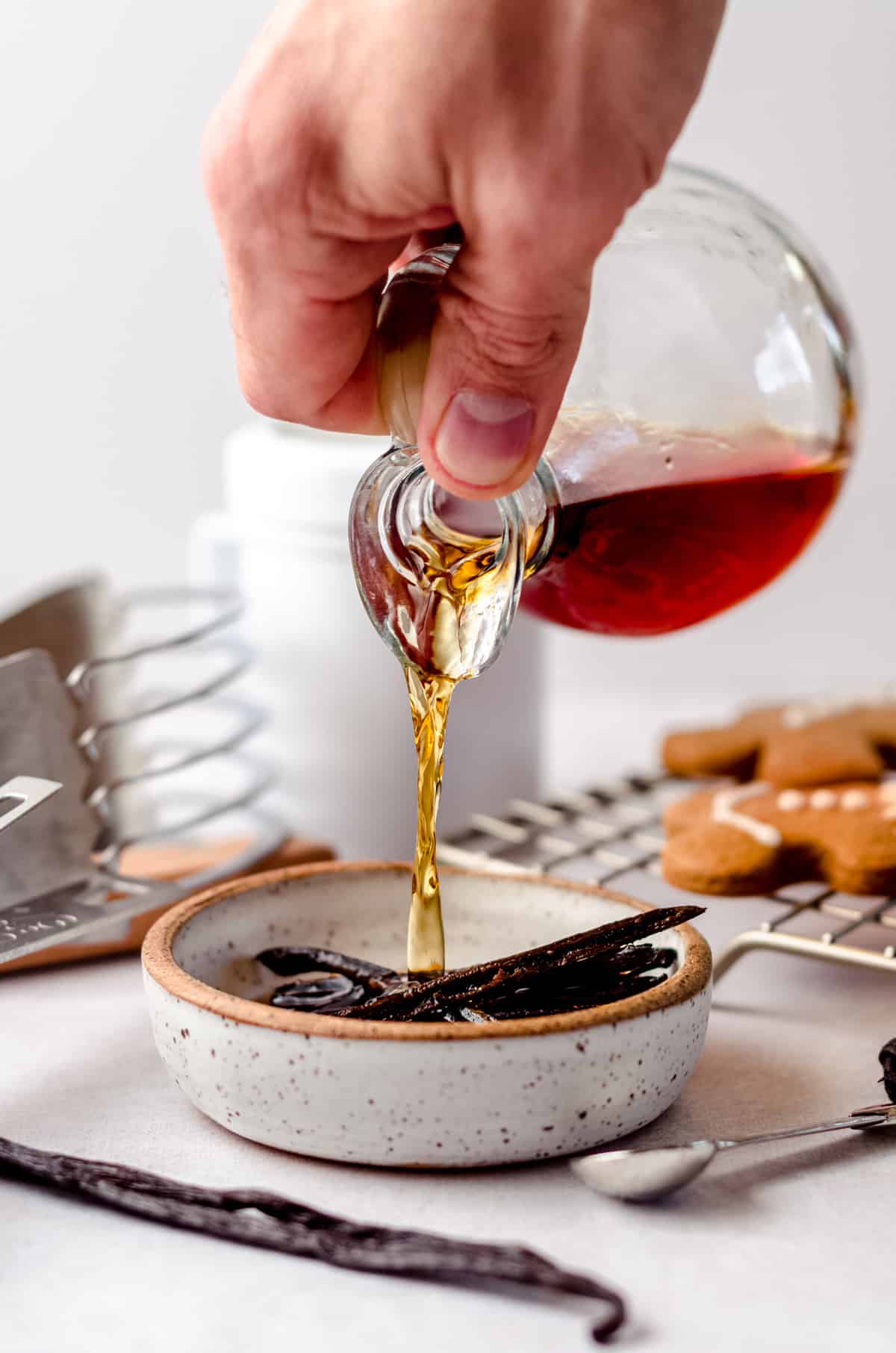 a hand pouring homemade vanilla extract into a bowl