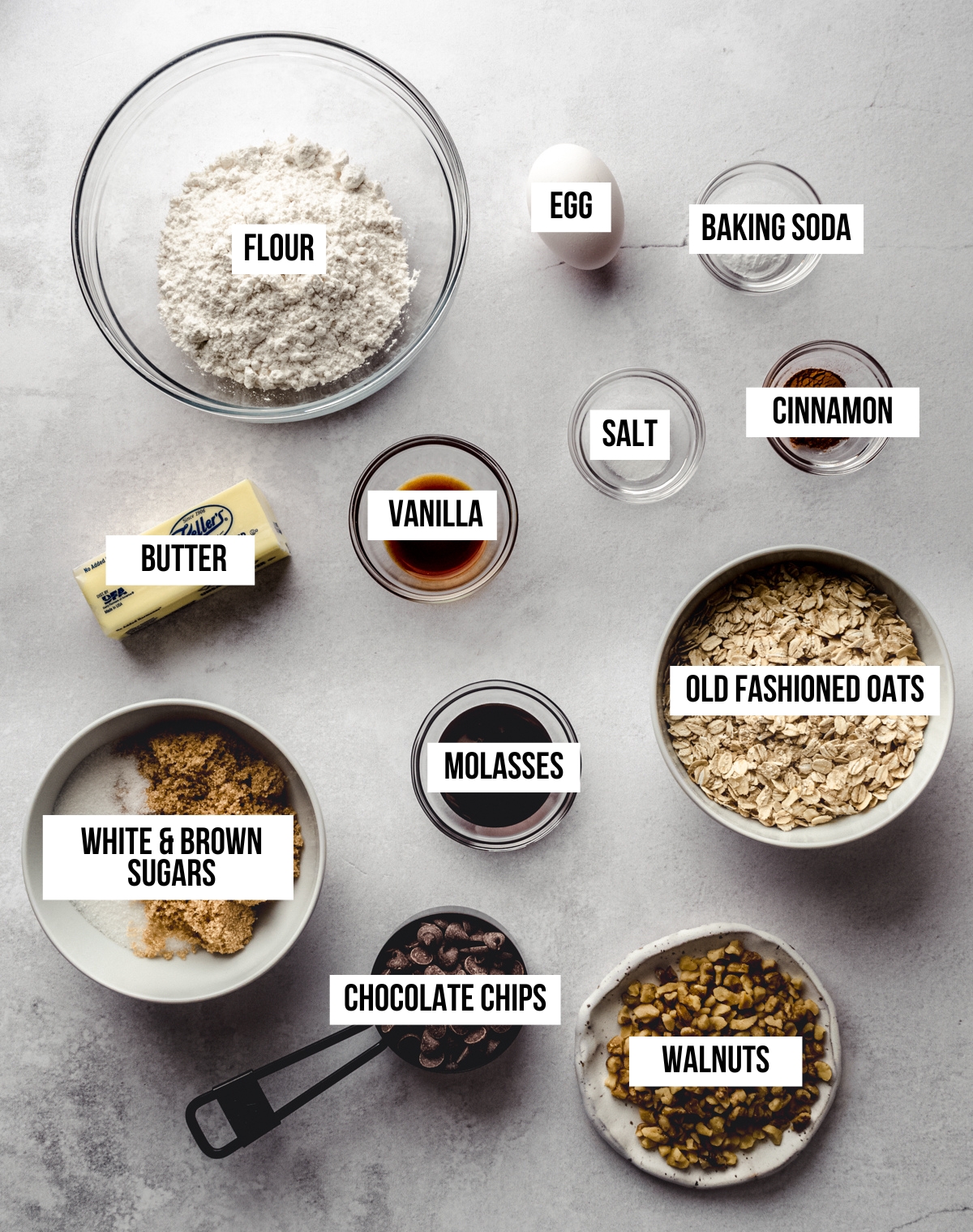 Aerial photo of ingredients to make oatmeal walnut chocolate chip cookies with text overlay labeling each ingredient.
