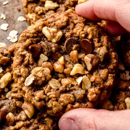 A photo of someone holding an oatmeal walnut chocolate chip cookie/